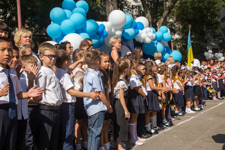ODESSA, UKRAINE September 1, 2018: September 1, day of the celebration of knowledge. Smiling happy first graders and their happy parents. Teacher in schoolyard holiday Beginning of the training yearのeditorial素材