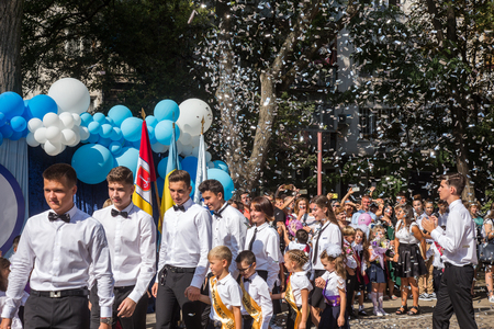 ODESSA, UKRAINE September 1, 2018: September 1, day of the celebration of knowledge. Smiling happy first graders and their happy parents. Teacher in schoolyard holiday Beginning of the training yearのeditorial素材