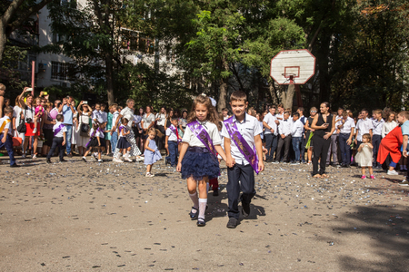 ODESSA, UKRAINE September 1, 2018: September 1, day of the celebration of knowledge. Smiling happy first graders and their happy parents. Teacher in schoolyard holiday Beginning of the training yearのeditorial素材