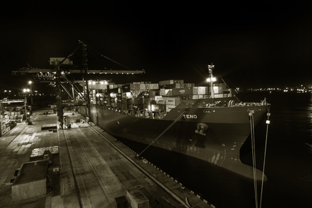 Odessa, Ukraine, Circus 2012: Sea commercial cargo port at night. Unloading, loading sea containers on a cargo ship at night. Container site with large sea freight containers with industrial goodsのeditorial素材