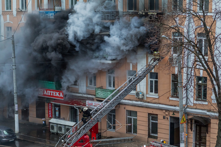 Odessa, Ukraine - Dec. 29, 2016: A fire in an apartment building. Strong bright light and clubs, smoke clouds window of their burning house. Firefighters extinguish fire in house. Work on fire stairsのeditorial素材