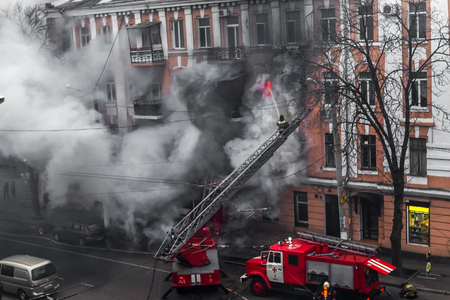 Odessa, Ukraine - Dec. 29, 2016: A fire in an apartment building. Strong bright light and clubs, smoke clouds window of their burning house. Firefighters extinguish fire in house. Work on fire stairsのeditorial素材
