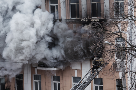 Odessa, Ukraine - Dec. 29, 2016: A fire in an apartment building. Strong bright light and clubs, smoke clouds window of their burning house. Firefighters extinguish fire in house. Work on fire stairsのeditorial素材