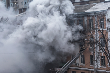 Odessa, Ukraine - Dec. 29, 2016: A fire in an apartment building. Strong bright light and clubs, smoke clouds window of their burning house. Firefighters extinguish fire in house. Work on fire stairsのeditorial素材