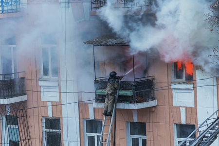 Odessa, Ukraine - Dec. 29, 2016: A fire in an apartment building. Strong bright light and clubs, smoke clouds window of their burning house. Firefighters extinguish fire in house. Work on fire stairsのeditorial素材