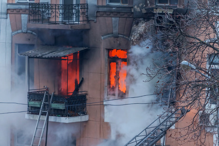 Odessa, Ukraine - Dec. 29, 2016: A fire in an apartment building. Strong bright light and clubs, smoke clouds window of their burning house. Firefighters extinguish fire in house. Work on fire stairsのeditorial素材