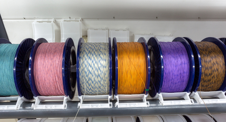 Industrial warehouse cable reels, coils with wound wire fiber optics. Fragment inside modern factory for production of power electrical cables and optical fibers. Finished products on  cable drumsの写真素材