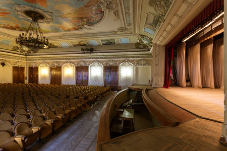 Mystical interior of old provincial Soviet theater of USSR. Stucco frescoes, nostalgic painting of walls and ceilings with fragments of revolutionary history USSR. Interior in luxurious Empire styleのeditorial素材