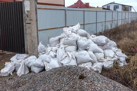 White construction sacks of construction waste are dumped in heap near fence under construction. Pollution concept. Ppile of garbage in garbage dump in landfill. Illegal waste dump Problem recyclingの写真素材