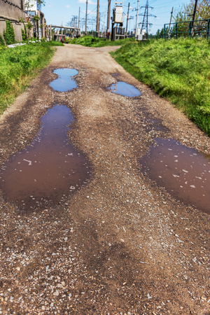Very bad quality road with potholes. Hole in asphalt, bad asphalt. Pit, unsafe, hole road. Transportation, destruction of roads, risk of movement by car concept. Bad roads conceptの写真素材