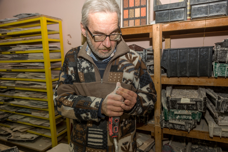 ODESSA, UKRAINE - DECEMBER 9, 2018: Marble mosaic workshop. Workers in process of choosing color fragment and making fragment of painting, panels of marble mosaics. Selective focusのeditorial素材