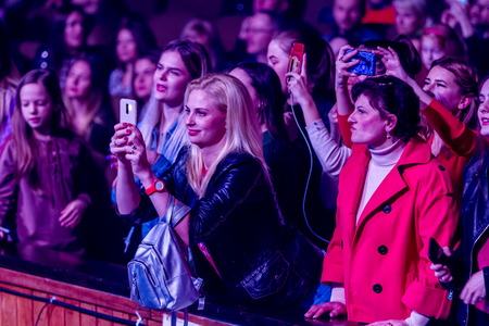 Odessa, Ukraine - April 12, 2019: Crowd of spectators at rock concert ALEKSEEV during music show. Crowds of happy people enjoy rock concert, raise their hands and clap their hands, audience on podiumのeditorial素材