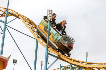 ODESSA, UKRAINE - MAY 6, 2019: Visitors ride road slides in an amusement park. Young friends on an exciting rollercoaster. Young people having fun in an amusement park. Scary fun on roller coasterのeditorial素材