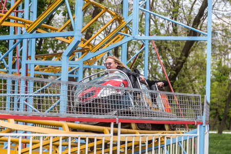 ODESSA, UKRAINE - MAY 6, 2019: Visitors ride road slides in an amusement park. Young friends on an exciting rollercoaster. Young people having fun in an amusement park. Scary fun on roller coasterのeditorial素材
