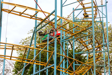 ODESSA, UKRAINE - MAY 6, 2019: Visitors ride road slides in an amusement park. Young friends on an exciting rollercoaster. Young people having fun in an amusement park. Scary fun on roller coasterのeditorial素材