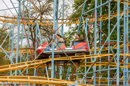 ODESSA, UKRAINE - MAY 6, 2019: Visitors ride road slides in an amusement park. Young friends on an exciting rollercoaster. Young people having fun in an amusement park. Scary fun on roller coasterのeditorial素材