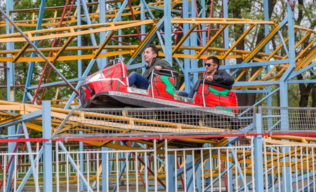 ODESSA, UKRAINE - MAY 6, 2019: Visitors ride road slides in an amusement park. Young friends on an exciting rollercoaster. Young people having fun in an amusement park. Scary fun on roller coasterのeditorial素材