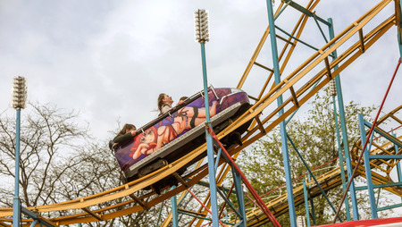 ODESSA, UKRAINE - MAY 6, 2019: Visitors ride road slides in an amusement park. Young friends on an exciting rollercoaster. Young people having fun in an amusement park. Scary fun on roller coasterのeditorial素材