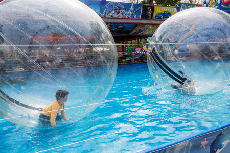 Odessa, Ukraine - May 6, 2019. Little children in an inflatable balloon, having fun on the water. The ball in the water - fascinating summer attractions for children. Water zorbingのeditorial素材