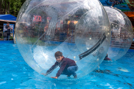 Odessa, Ukraine - May 6, 2019. Little children in an inflatable balloon, having fun on the water. The ball in the water - fascinating summer attractions for children. Water zorbingのeditorial素材
