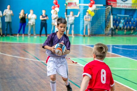 ODESSA, UKRAINE - MAY 18, 2019: Young children play rugby during final games of championship in hall. Children's sport. Children play rugby 5. Fight for victory of children in rugbyのeditorial素材