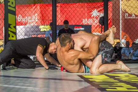 ODESSA, UKRAINE-June 30, 2019: Fighters of MMA boxers are fighting without rules in cage ring of octagons. MMA fighters in ring at  championship. Look at boxing fights without rules through metal cageのeditorial素材