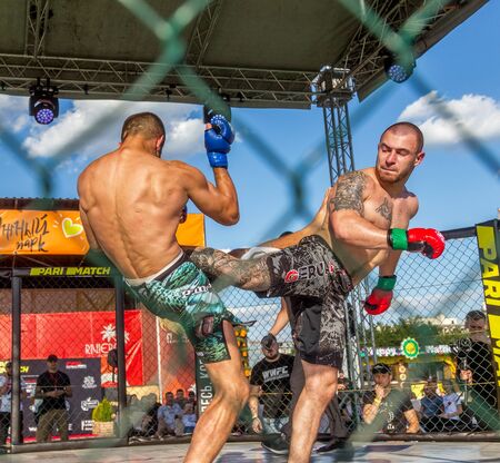 ODESSA, UKRAINE-June 30, 2019: Fighters of MMA boxers are fighting without rules in cage ring of octagons. MMA fighters in ring at  championship. Look at boxing fights without rules through metal cageのeditorial素材