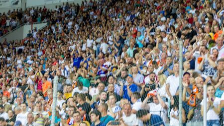 ODESSA UKRAINE - July 28, 2019: Out of focus, not sharp sport background - spectators at stadium. Crowds of fans in stands of football stadium during match Tribune with fans. Stands with football fansのeditorial素材