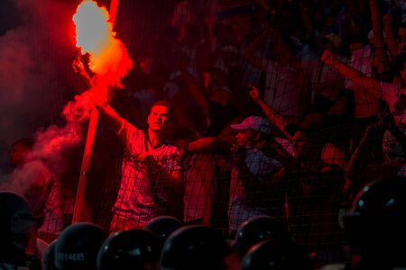 ODESSA, UKRAINE -July28,2019: Fanatical fans in stand during game of eternal rivals. Fans on racks are happy, glow with fire and waving flag. Fiery show at stadium. Fan of hooligan light fiery flasheのeditorial素材