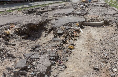 Large cracks, chips. Broken asphalt shifted landslide after flood. Destroyed road by water. Groundwater flushing. Concept of destruction of roads from nature. Consequences of flood. Broken  streetの写真素材