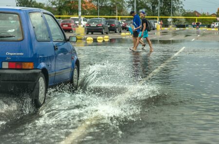Odessa, Ukraine - August 9, 2019: driving car on flooded road during flood caused by torrential rains. Cars float on water, flooding streets. Splash on the car. Flooded city road with a large puddleのeditorial素材