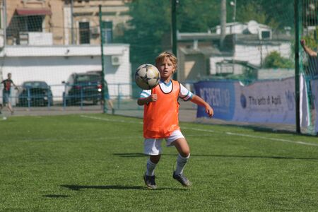 ODESSA, UKRAINE - September 7, 2019: little children in training play soccer. Younger boys kick soccer at the playground. Children play football on a green futsal fieldのeditorial素材