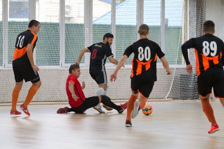 Odessa, Ukraine - October 6, 2019: Unidentified local team players play indoor soccer futsal tournament on the parquet floor. The right moment of a sports soccer game in an indoor hall, indoor soccerのeditorial素材