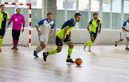 Odessa, Ukraine - October 11, 2019: Unidentified local team players play indoor soccer futsal tournament on the parquet floor. The right moment of sports soccer game in an indoor hall, indoor soccerのeditorial素材