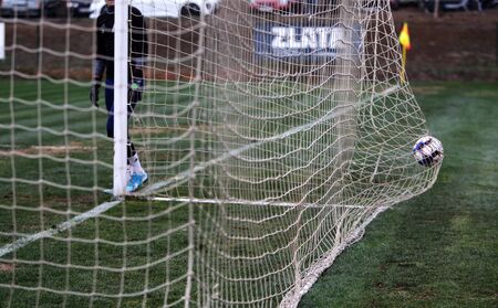 ODESSA, UKRAINE - CIRCA 2019: A goalkeeper of a local football team makes a save while playing in a regional derby championship on a bad football field. Soccer goal, goal netのeditorial素材