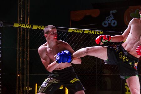 ODESSA, UKRAINE-June 30, 2019: Fighters of MMA boxers are fighting without rules in cage ring of octagons. MMA fighters in ring at championship. Look at boxing fights without rules through metal cageのeditorial素材