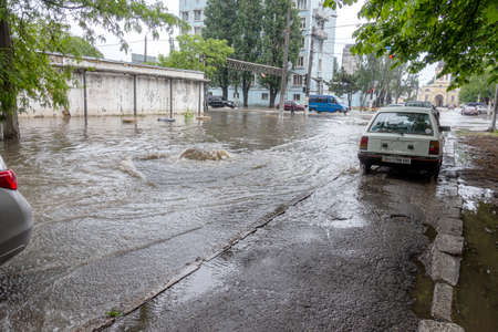 Odessa, Ukraine - May 28, 2020: driving car on flooded road during flood caused by torrential rains. Cars float on water, flooding streets. Splash on car. Flooded city road with large puddleのeditorial素材