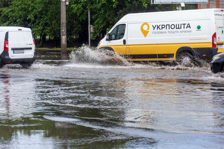 Odessa, Ukraine - May 28, 2020: driving car on flooded road during flood caused by torrential rains. Cars float on water, flooding streets. Splash on car. Flooded city road with large puddleのeditorial素材