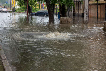Odessa, Ukraine - May 28, 2020: driving car on flooded road during flood caused by torrential rains. Cars float on water, flooding streets. Splash on car. Flooded city road with large puddleのeditorial素材