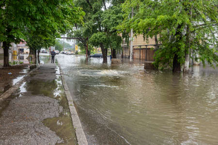 Odessa, Ukraine - May 28, 2020: driving car on flooded road during flood caused by torrential rains. Cars float on water, flooding streets. Splash on car. Flooded city road with large puddleのeditorial素材