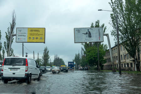 Odessa, Ukraine - May 28, 2020: driving car on flooded road during flood caused by torrential rains. Cars float on water, flooding streets. Splash on car. Flooded city road with large puddleのeditorial素材