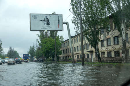 Odessa, Ukraine - May 28, 2020: driving car on flooded road during flood caused by torrential rains. Cars float on water, flooding streets. Splash on car. Flooded city road with large puddleのeditorial素材