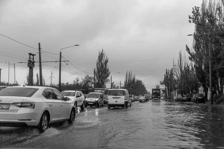 Odessa, Ukraine - May 28, 2020: driving car on flooded road during flood caused by torrential rains. Cars float on water, flooding streets. Splash on car. Flooded city road with large puddleのeditorial素材