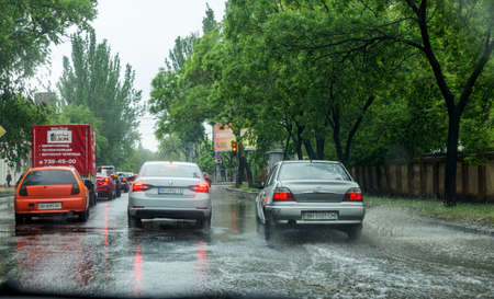 Odessa, Ukraine - May 28, 2020: driving car on flooded road during flood caused by torrential rains. Cars float on water, flooding streets. Splash on car. Flooded city road with large puddleのeditorial素材