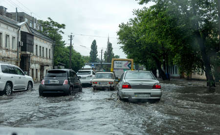 Odessa, Ukraine - May 28, 2020: driving car on flooded road during flood caused by torrential rains. Cars float on water, flooding streets. Splash on car. Flooded city road with large puddleのeditorial素材