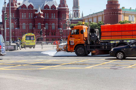 MOSCOW, RUSSIA - June 24, 2020: Citys road services disinfect streets in center of Moscow during COVID-19 coronavirus epidemic in Russia. Street watering machine washes the asphalt of city roadのeditorial素材