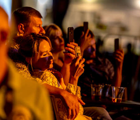 ODESSA, UKRAINE - CIRKA 2020: Spectators at concert in theater take pictures of performance of their...