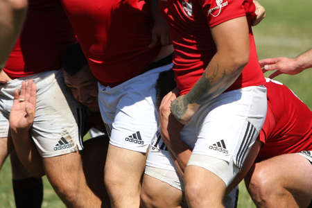 Odessa, Ukraine - August 29, 2020: Odessa National Team CREDO (red) - Kiev Antares (black) rugby 7s. Sharp aggressive fight of male rugby players for ball. Dynamic play on green grass field of stadiumのeditorial素材