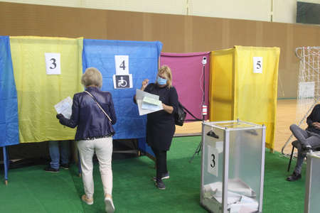 ODESSA, UKRAINE -25.10.2020 - Elections in Ukraine. Electoral platform for elections of local councilors during the COVID-19 coronavirus pandemic. People wearing masks and gloves with voting ballotsのeditorial素材