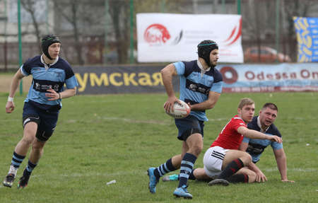 ODESSA, UKRAINE - April 17, 2021: Rugby Cup 7. Odessa Polytechnic Derby - blue, CREDO - red. Tense moment of men's rugby match. Dramatic and challenging men's rugby derby. Men fight on rugby fieldのeditorial素材